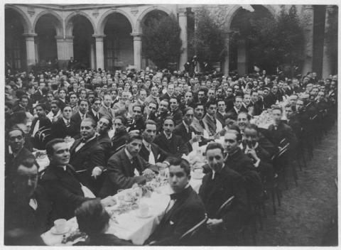 Primera imagen del registro Grupo de hombres sentados frente a largas mesas